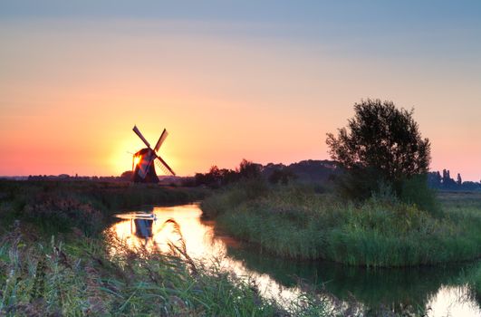 sunrise with sun behind Dutch windmill, Holland