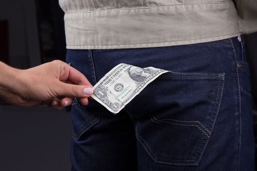 Thief takes out a dollar out of the pocket