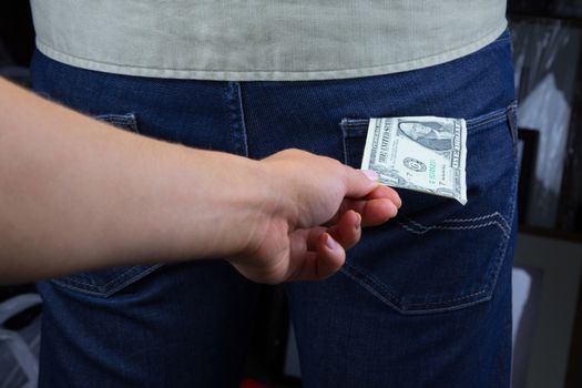 Thief takes out a dollar out of the pocket