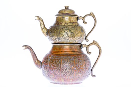 Isolated antique engraved copper Turkish teapot with double stacked kettles allowing tea to be brewed in one while hot water from the larger kettle is used to dilute individual cups of tea to taste