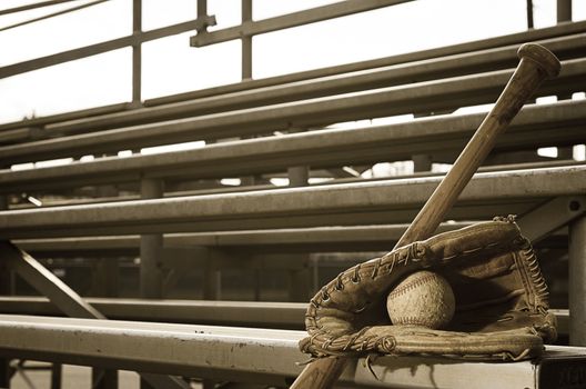 High school baseball practice with ball in glove and bat on bleachers.  