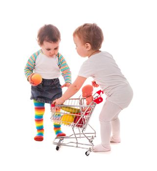 Little girls play with shopping trolley and doll. Grocery store playing