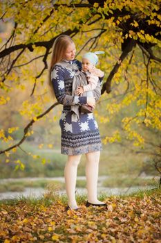 Mother walking with  baby in sling in the park