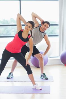 Portrait of two smiling people doing power fitness exercise at yoga class in fitness studio