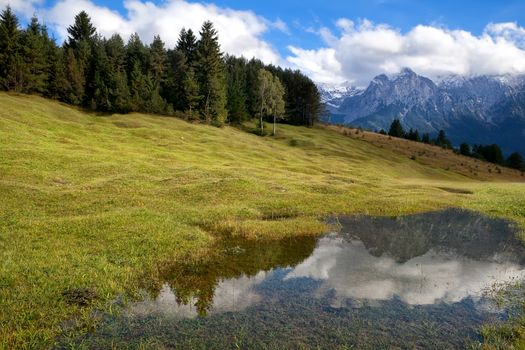 high Alps and blue sky reflected in wild lake, Bavaria, Germany
