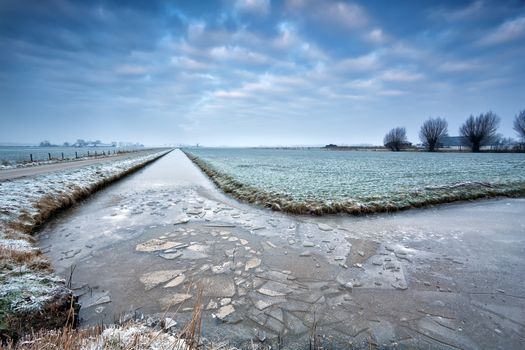 broken ice on frozen river in winter Dutch farmland, Groningen, Netherlands