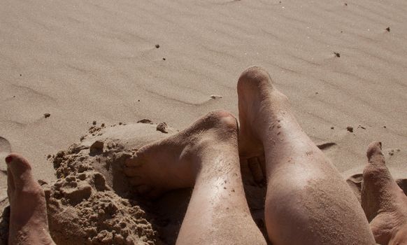 Sandy feet showing a couple enjoying the beach on their vacation.