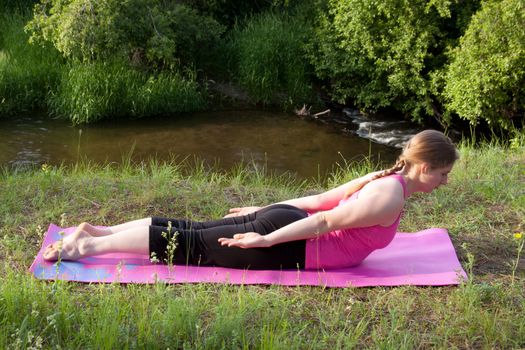 A pretty young girl doing Yoga poses in the peaceful setting of a woodland stream.