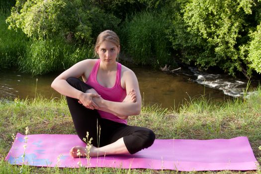 A pretty young girl doing Yoga poses in the peaceful setting of a woodland stream.