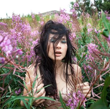 Seminude beautiful girl among the flowers and old concrete wall background