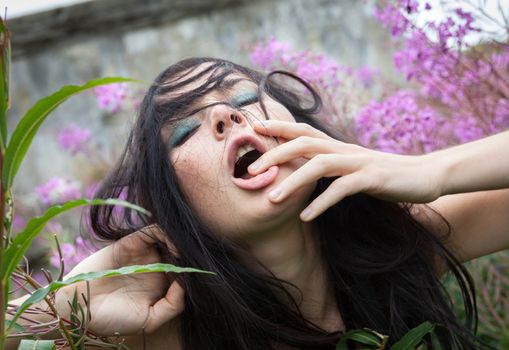  beautiful girl among the flowers on the old concrete wall background