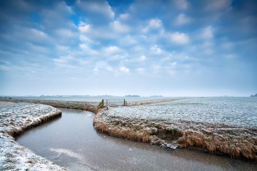 frozen canal on Dutch winter farmland, Groningen, Netherlands