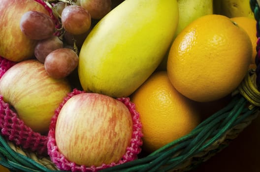 Gift fruit basket filled with grapes, apples, mangoes, and oranges