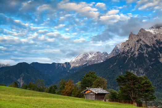 hut on meadow and Karwendel mountain range by Mittenwald, Germany