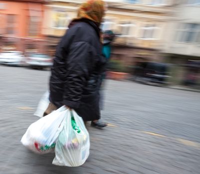 Old woman with plastic bags. Intentional motion blur