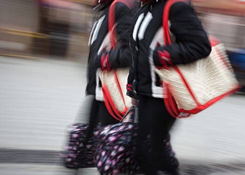 Two young woman at rush hour walking in the street. Intentional motion blur
