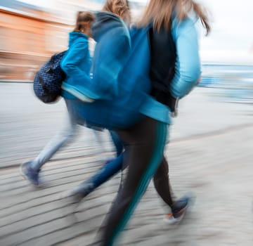 Abstract image of  young people group going along the street. Intentional motion blur