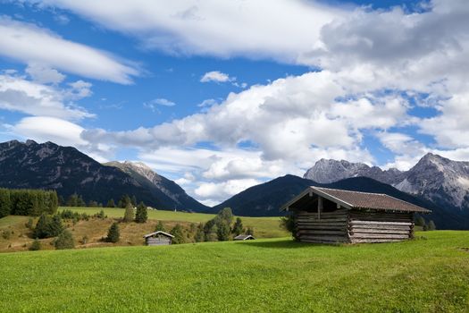 few huts on greem meadows over blue sky in Bavarian Alps