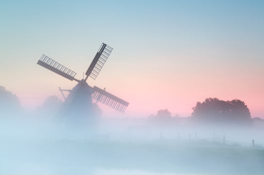charming Dutch windmill in dense sunrise fog, Holland