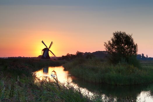 shining windmill during sunrise over river, Holland