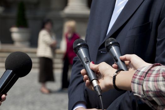 Interview with media microphone held in front of businessman, spokesman or politician