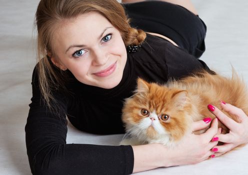 The young nice girl holds a red Persian cat on hands