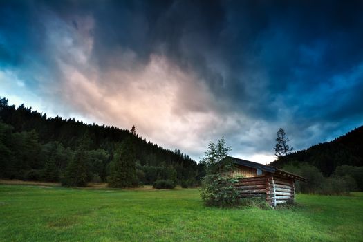 alpine wooden hut during stormy sunset, Bavaria, Germany