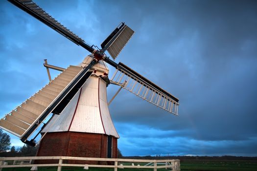 white Dutch windmill in sunset light after the storm