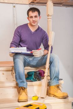 young contractor sitting on wooden ladder in home