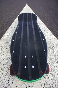 Vintage Style Longboard Black Skateboard on an Empty Asphalt Desert Road