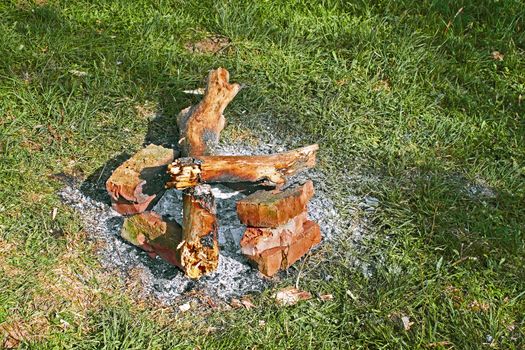 Remains of a bonfire on the green grass as an example of environmental negligence