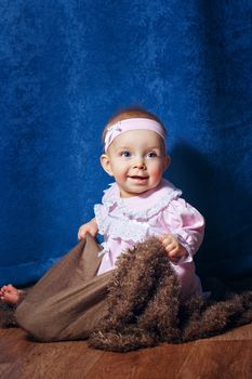 Pretty blue-eyed girl in a pink dress sitting on the floor