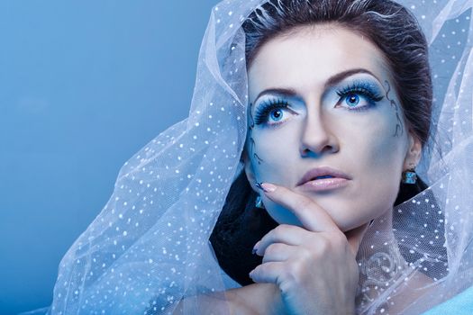 Attractive young girl with a theatrical makeup on the face in the image fabulous snow queen