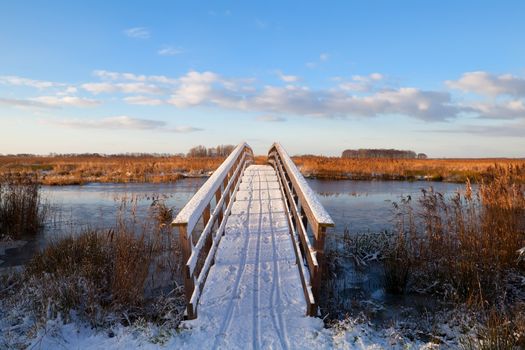 wooden bridge through river in snow during winter, Groningen, Netherlands