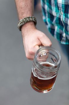 Close up of a mans hand holding a stein of beer for Octoberfest.  Shallow depth of field.