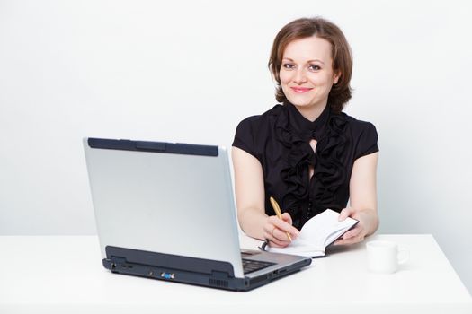 attractive girl in a black dress with a laptop at the table