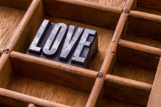 Metal letterpress in an old typesetter's drawer showing the word "LOVE"