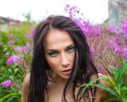 Seminude beautiful girl among the flowers and old concrete wall background