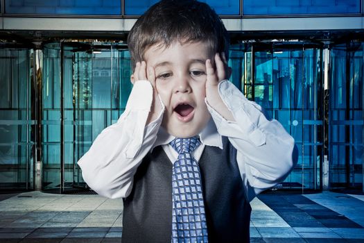 Expression, child dressed businessman with hands in his tie and skyscrapers in the background