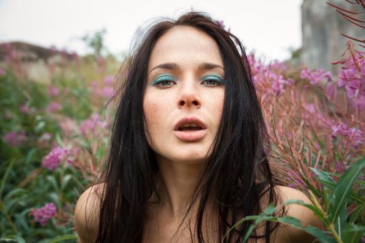 Seminude beautiful girl among the flowers and old concrete wall background