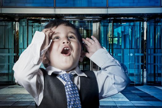 Office, child dressed businessman with hands in his tie and skyscrapers in the background