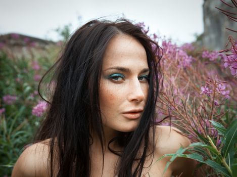 Seminude beautiful girl among the flowers and old concrete wall background