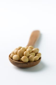 Close-up of soya beans on wooden spoon over white background