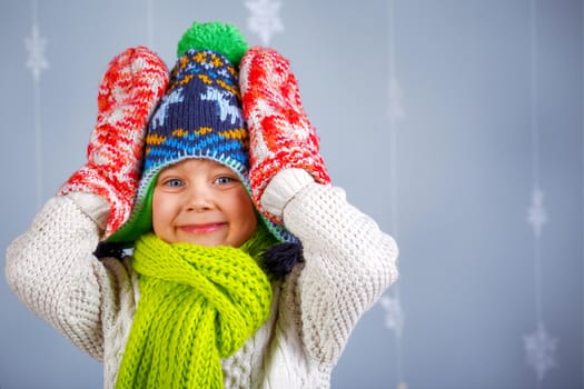 Winter Fashion. Portrait of adorable happy boy in winter hat gloves and sweater in studio.