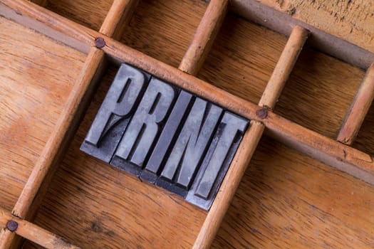 Metal letterpress in an old typesetter's drawer showing the word "PRINT"