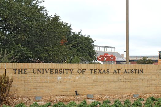 AUSTIN, TEXAS - FEBRUARY 2 2014: Sign for the University of Texas at Austin with Darrell K Royal-Texas Memorial Stadium in the background. Founded in 1883, it is one of the top 20 schools in the USA.