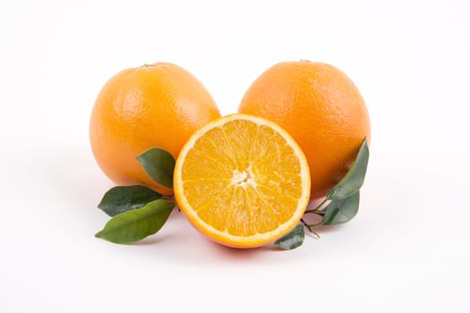 Fresh oranges with half and leaves on a white background.