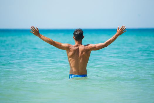 Back view of athletic young man on beach vacation
