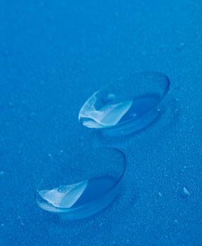 Two Contact Lenses with Water Droplets isolated on Blue background