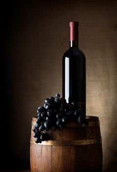 Bottle of red wine, grapes and wooden barrel